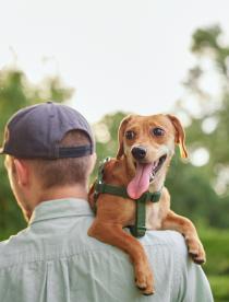 Photo of a man carrying a dog over his shoulder.