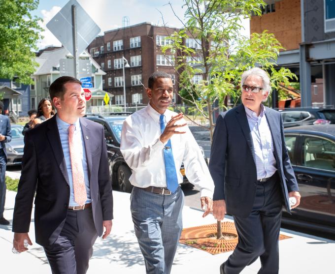 Photograph of Rochester Mayor Malik Evans walking outside with two men.