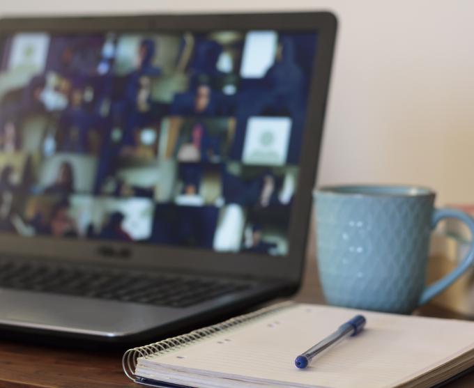 Getty Images photo of a notepad and cup of coffee next to an open laptop with a virtual meeting underway.