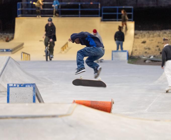 A photo of a skateboarder performing a kickflip at ROC City Skatepark.