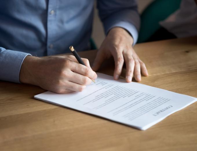 Photo of a person signing a document.