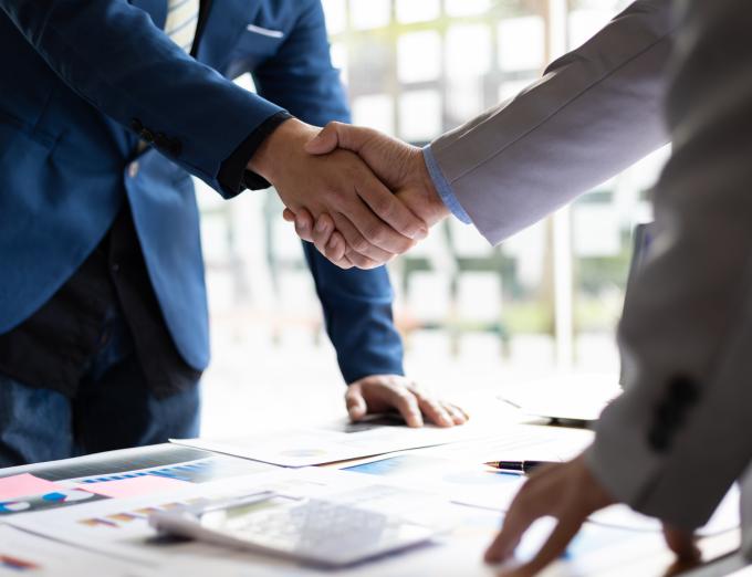 Photo of two people shaking hands over business documents.