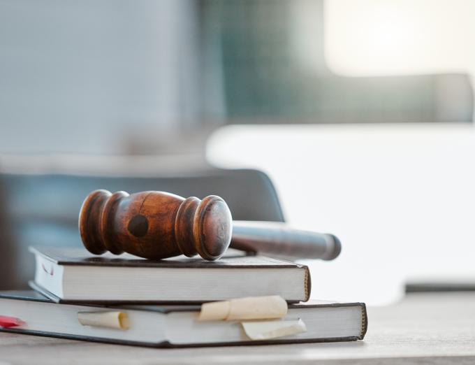 Photo of a gavel on top of books stacked on a desk.