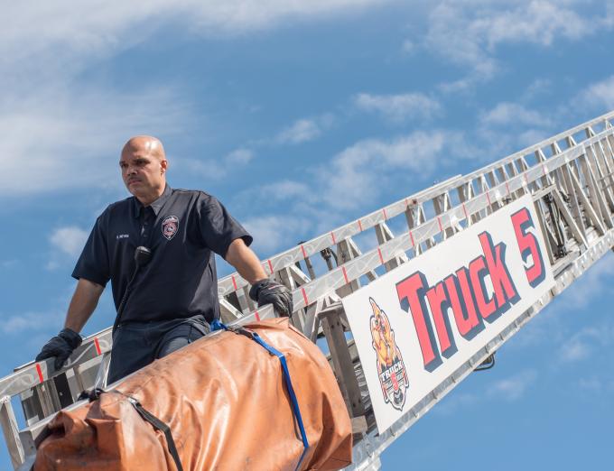 Photo of a Rochester firefighter descending a ladder.