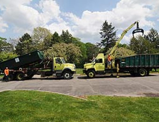 Photo of two garbage trucks in a parking lot.