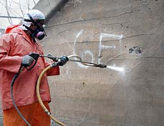 Photo of a worker removing graffiti.