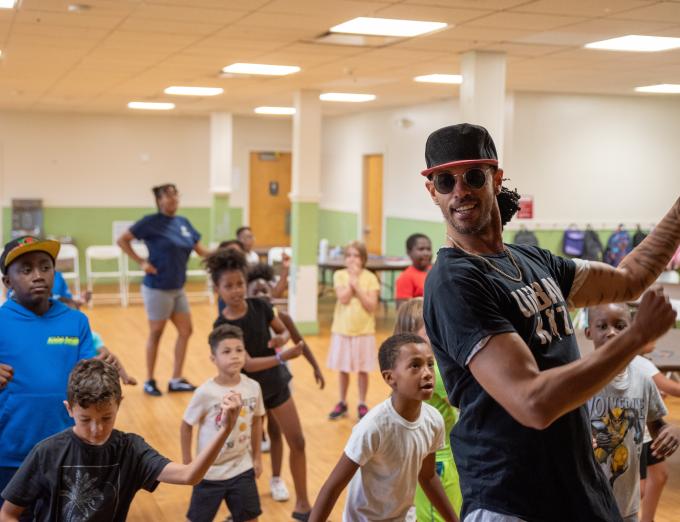 Photo of a teacher leading a group of students in dance instruction.