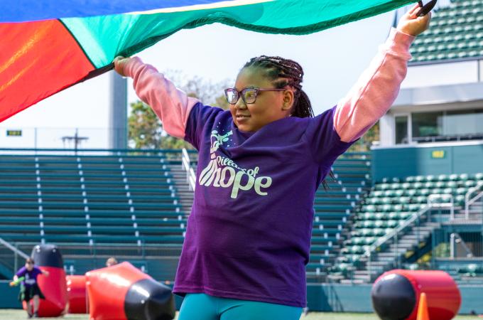 Young girl in a Pillars of Hope t-shirt participating in a parachute activity