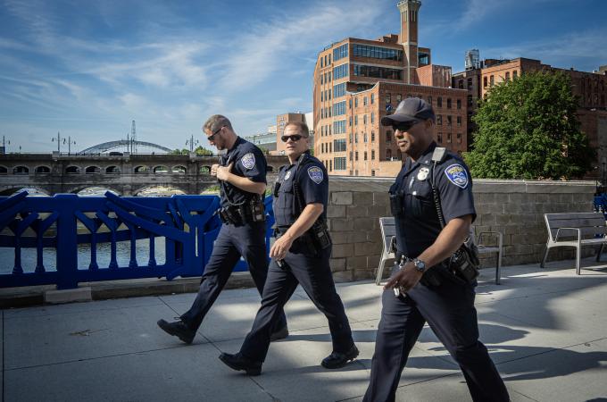 Photo of three Rochester police officers walking across the Main Street Bridge downtown.