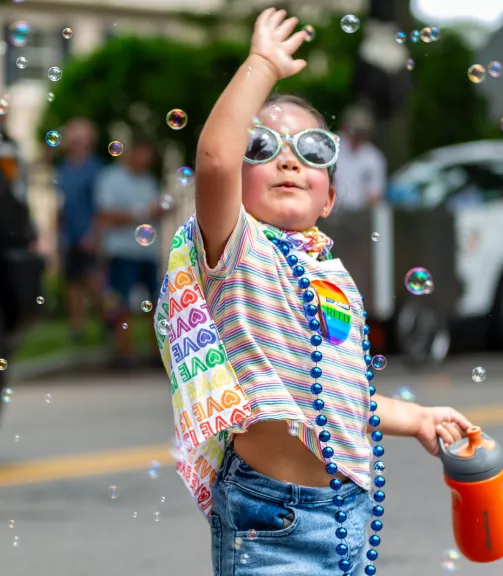 Photo of a girl playing with bubbles at the Rochester Pride Parade.