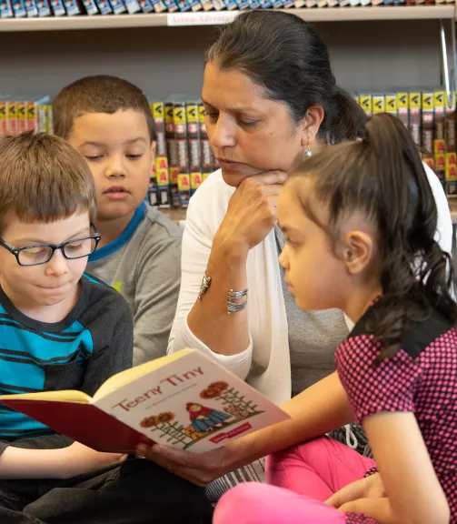 Photo of a woman reading to children in a library.